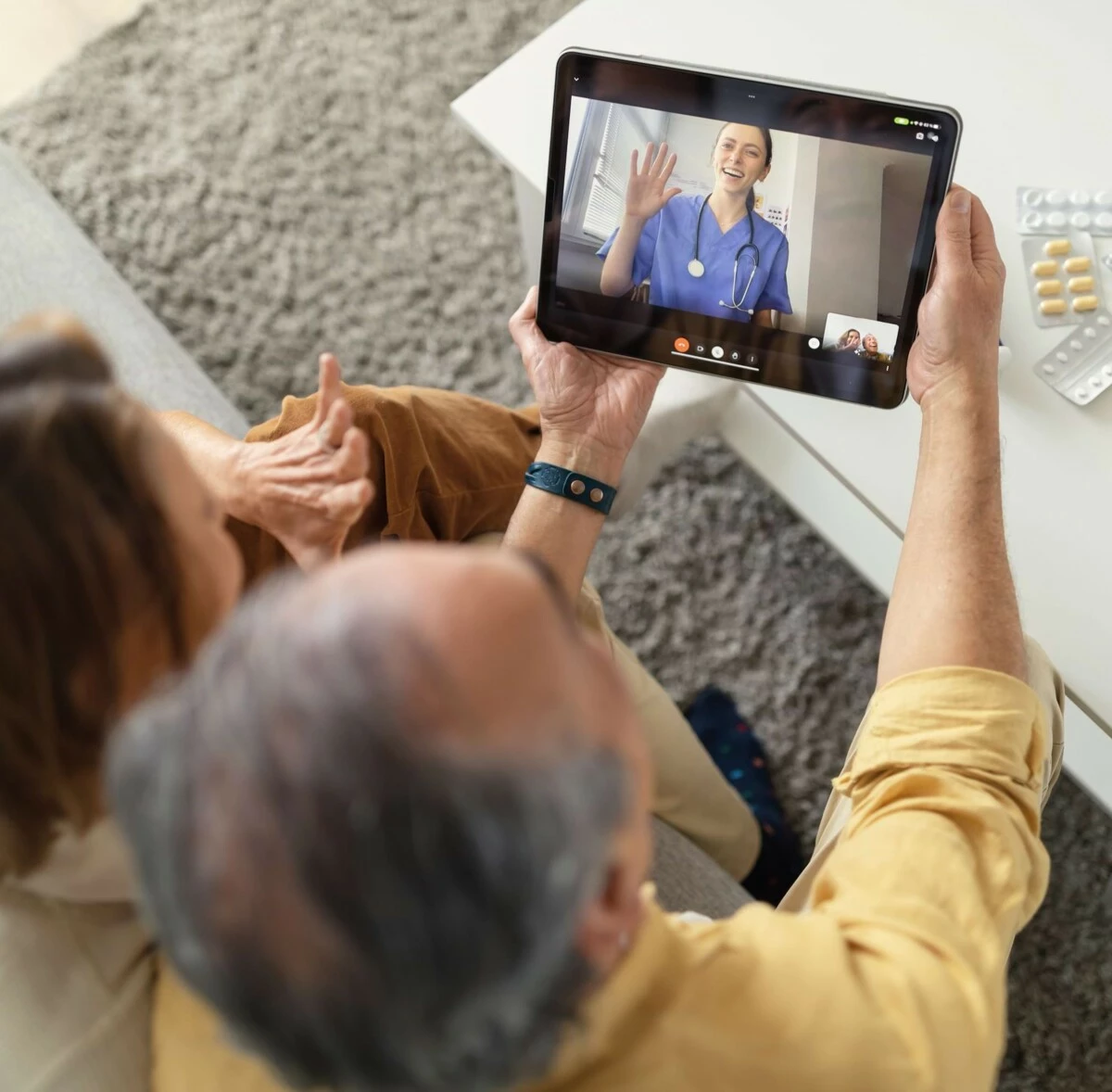 Ein Ehepaar sitzt auf der Couch und führt eine Video Beratung mit einer Ärztin per Videochat durch.