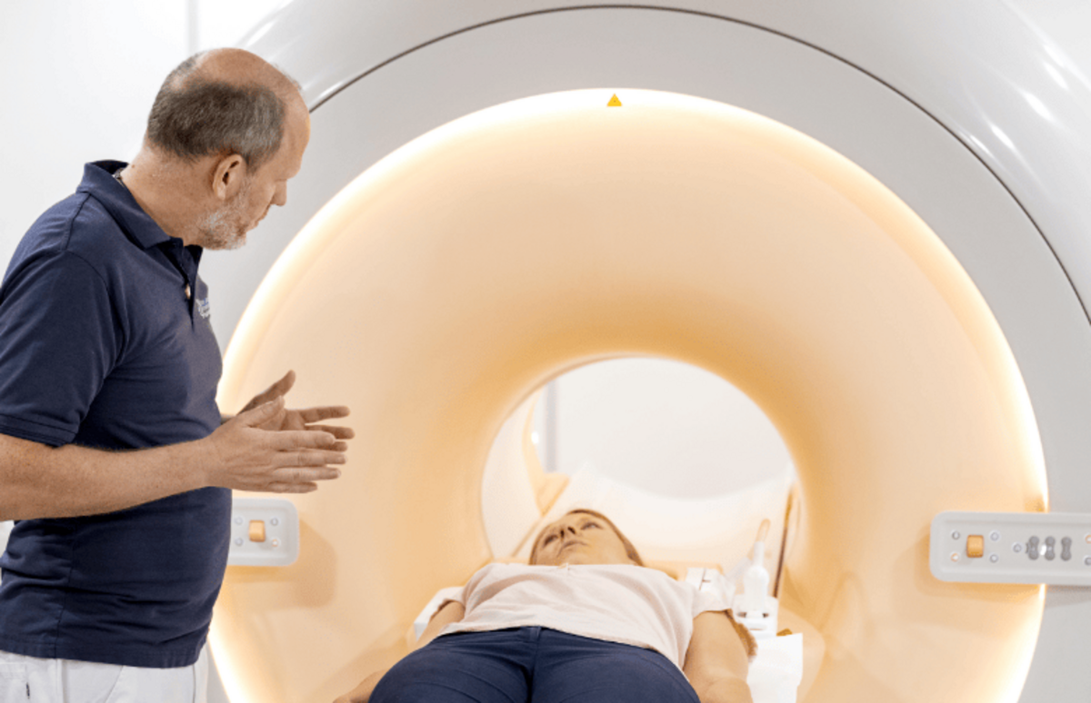 Ein Mitarbeiter richtet eine Patientin für die Magnetresonanztomographie (MRT) aus, um hochauflösende Bilder für die Untersuchung von Gelenken, Weichteilen und dem Nervensystem zu erstellen.
