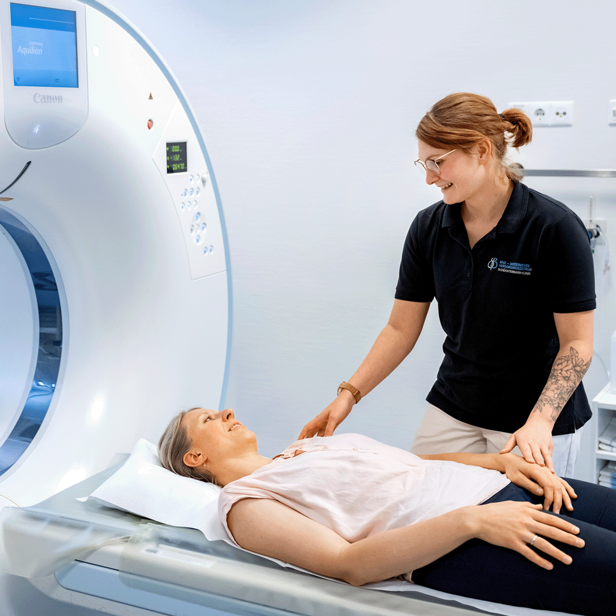 Eine Patientin wird für die Computertomographie (CT) ausgerichtet, während die Mitarbeiterin die Position anpasst, um präzise Schnittbilder für die Diagnose zu erstellen
